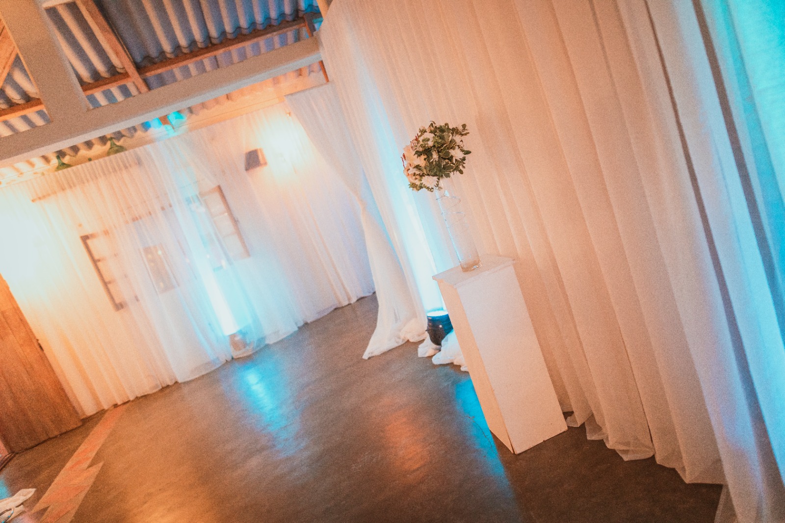 Salón con cortinados blancos y arreglo floral, de noche
